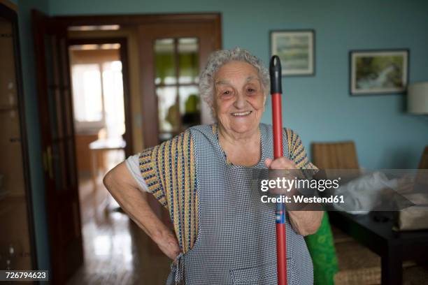 portrait of smiling senior woman holding stick of cleaning mop - hausmann oder hausfrau stock-fotos und bilder