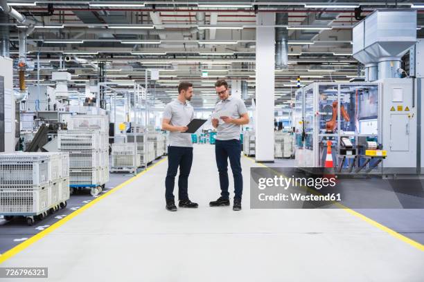 two men talking in factory shop floor - ipad industrie stock-fotos und bilder