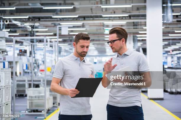 two men talking in factory shop floor - papierwerk stock-fotos und bilder