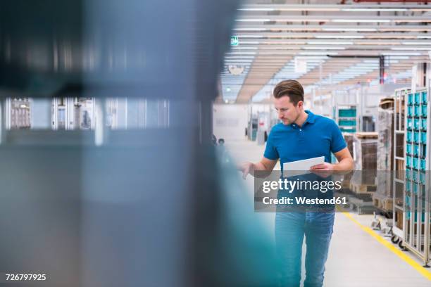 man with tablet looking at tugger train in industrial hall - überprüfung stock-fotos und bilder