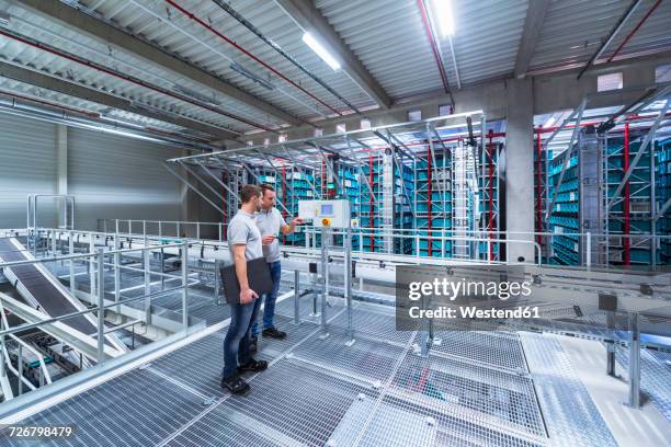 two men in automatized high rack warehouse - weitwinkel stock-fotos und bilder