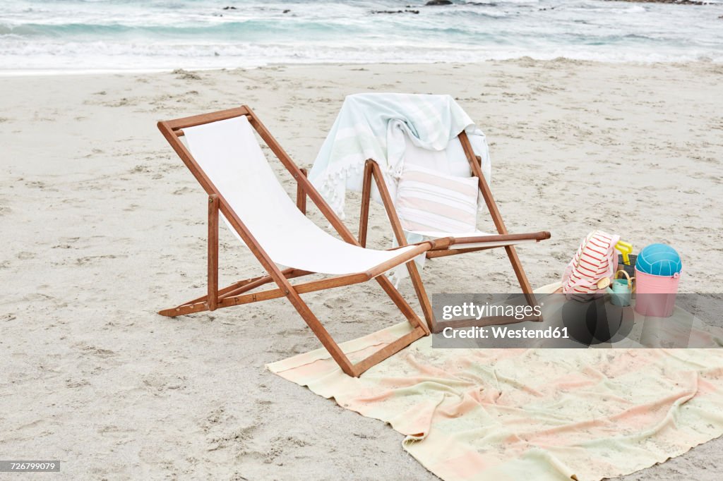 Empty sun loungers on the beach with towels and toys