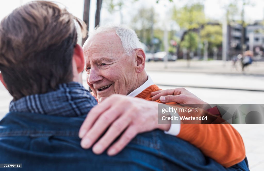 Smiling senior man looking at adult grandson outdoors