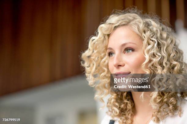portrait of smiling blond businesswoman with ringlets - pijpenkrul stockfoto's en -beelden