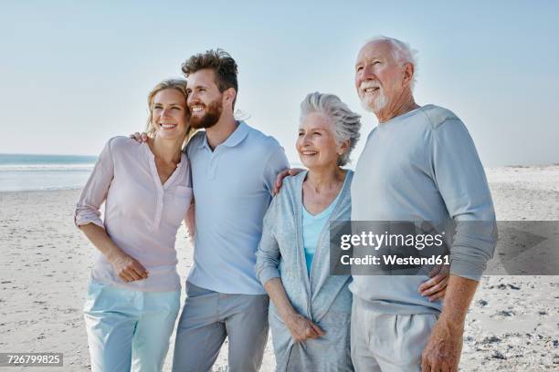 smiling senior couple with adult children on the beach - daughter in law stock pictures, royalty-free photos & images