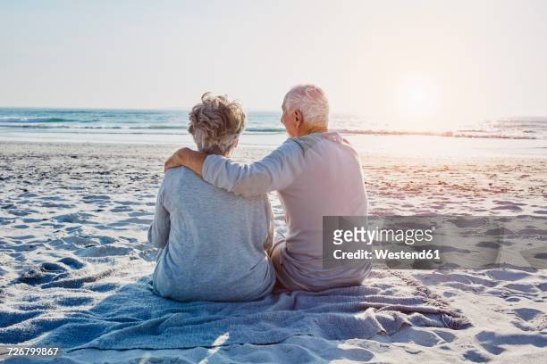 senior couple sitting on the beach looking at distance - indulgence stockfoto's en -beelden