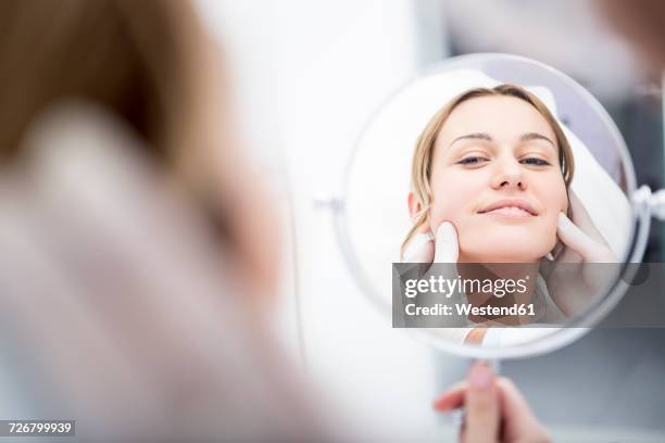 aesthetic surgery, woman looking in mirror - handspiegel stock-fotos und bilder