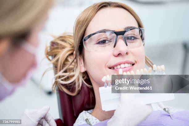 woman at the dentist choosing color for teeth whitening - teeth whitening stock-fotos und bilder