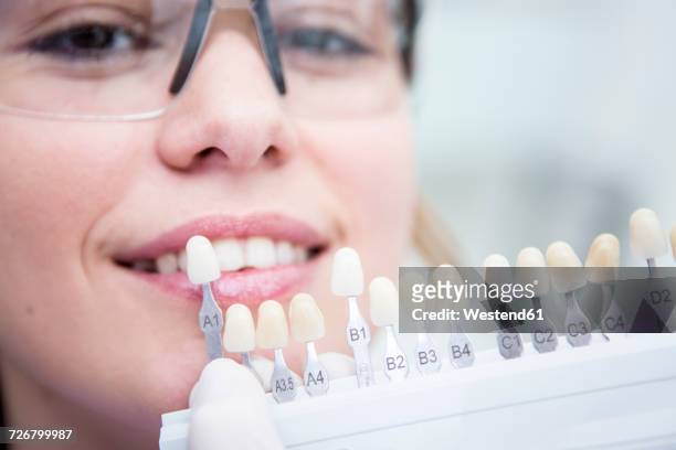 woman at the dentist choosing color for teeth whitening - zahnaufhellung stock-fotos und bilder