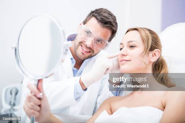 aesthetic surgery, woman looking in mirror - chirurgo plastico foto e immagini stock