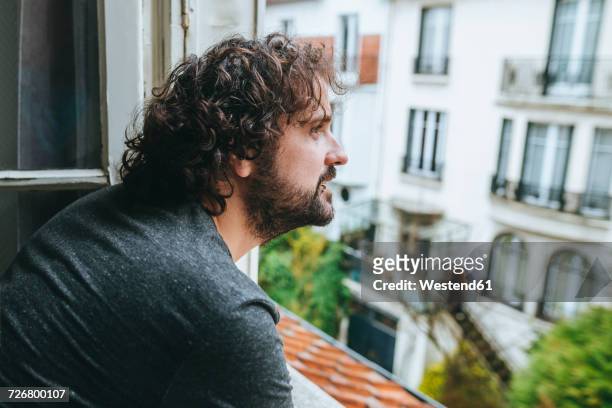 man looking through opened window at home - solo un uomo di età media foto e immagini stock