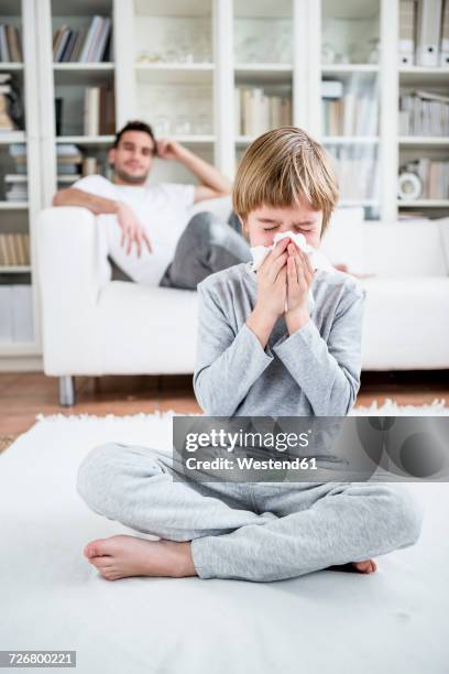 boy blowing his nose at home - child sitting stock-fotos und bilder