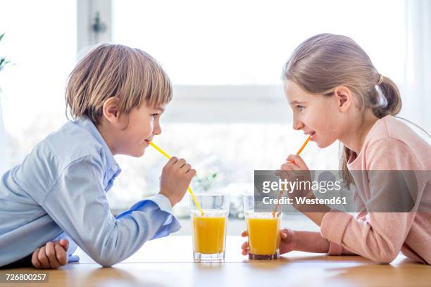 brother and sister drinking orange juice - orange juice stock-fotos und bilder