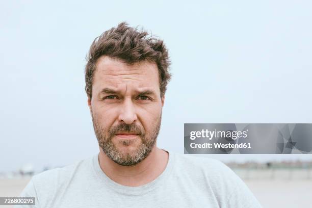 portrait of bearded man on the beach - froncer les sourcils photos et images de collection
