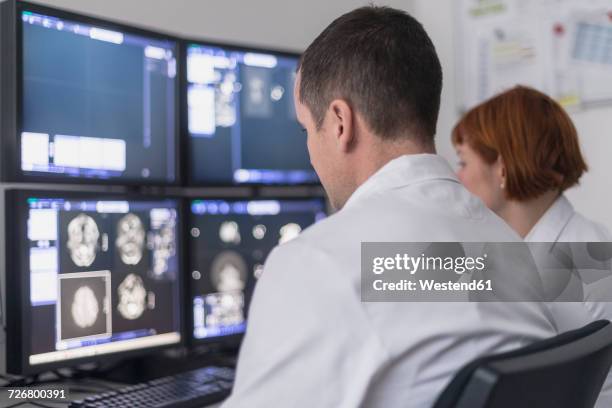 two doctors looking at x-ray images on computer screen - medical judge stock-fotos und bilder