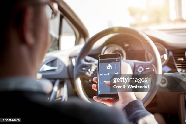 man in car adjusting devices at home via smartphone - holding smart phone stock pictures, royalty-free photos & images
