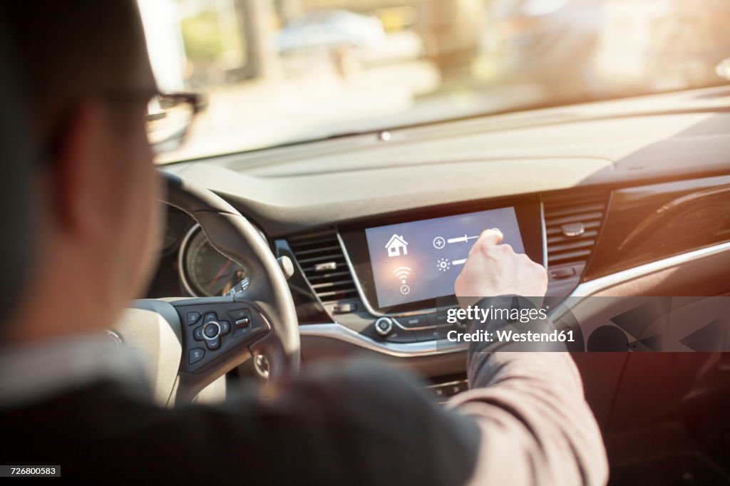 Man in car adjusting devices at home via smartphone