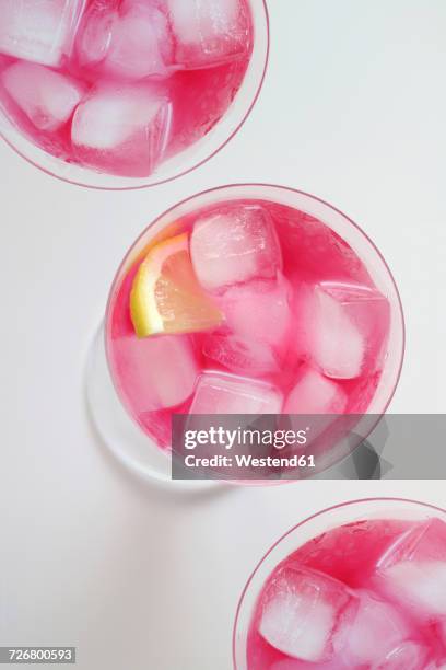 glasses of cocktail 'pink flamingo' with icecubes and lemon slice - pink drink stock pictures, royalty-free photos & images