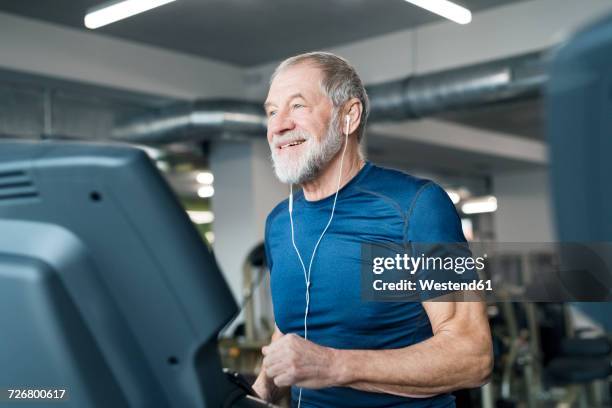 fit senior man on treadmill working out in gym - running on treadmill stockfoto's en -beelden