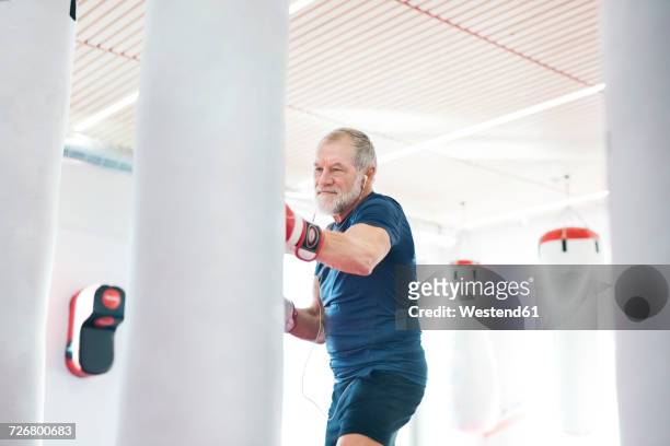 fit senior man in boxing gloves fighting - aanvallen sporten stockfoto's en -beelden