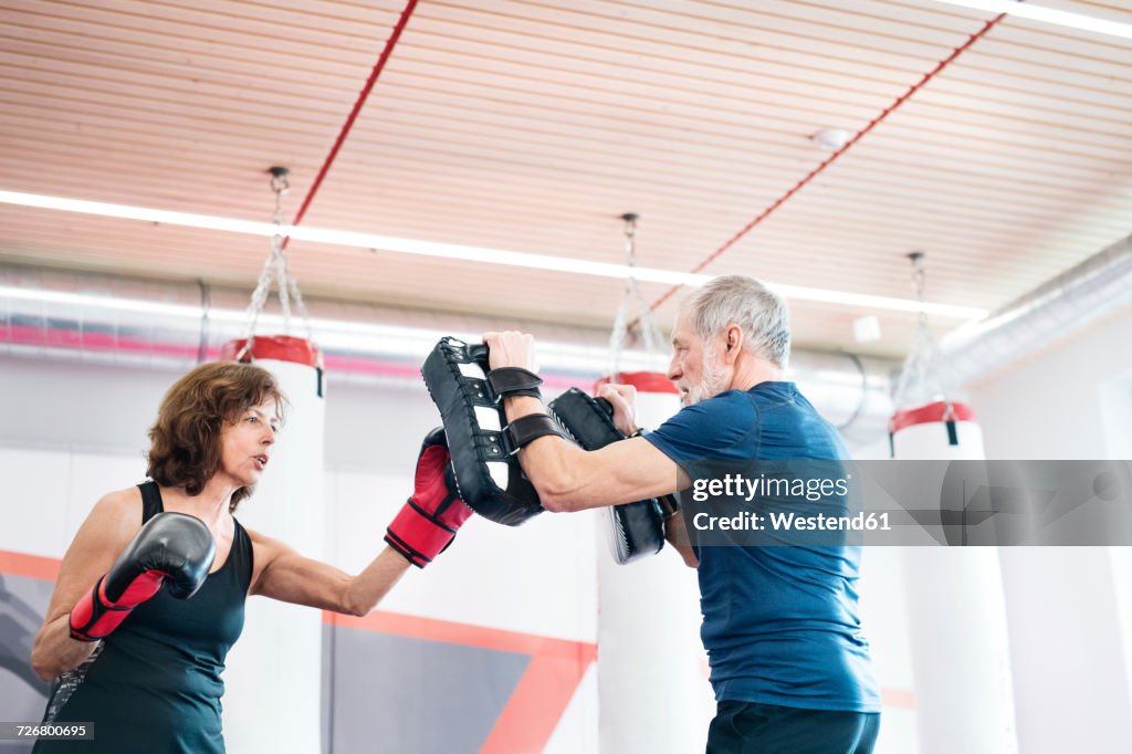 Fit senior woman boxing with her coach