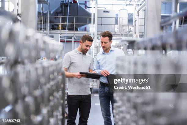 two men with tablet talking in factory shop floor - tablet production stock-fotos und bilder