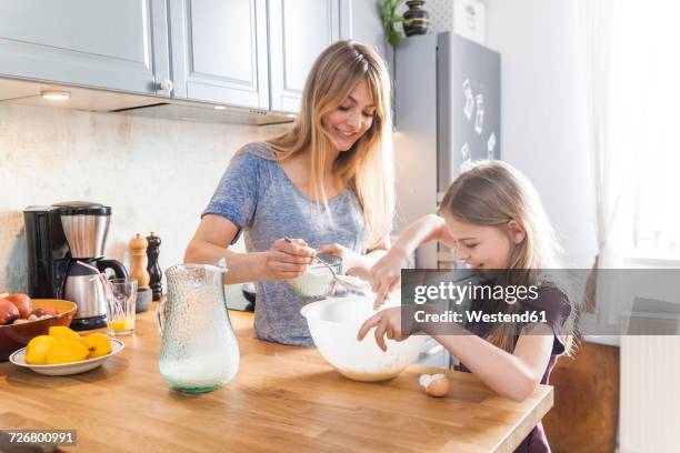 mother and daughter preparing pancakes in kitchen - children back stock-fotos und bilder
