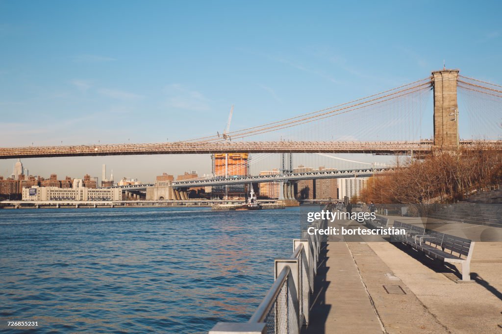 Bridges Over East River And Promenade Against Clear Blue Sky