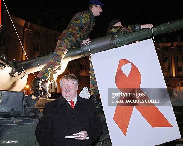 Belgian Defence Minister Andre Flahaut is pictured in front of Belgian army tank on which soldiers tie a banner with the Red Ribbon sign to mark...