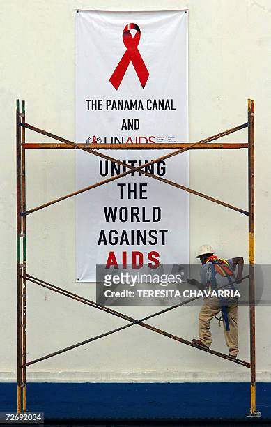 Un trabajador del Canal de Panama coloca un cartel promocional de la campana contra el SIDA en la caseta de control de las Esclusas de Miraflores el...
