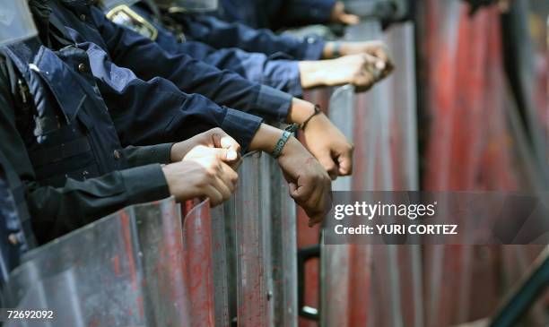 Riot police members stand guard after being sprayed with red paint during a protest against the inauguration of Mexican new president Felipe Calderon...