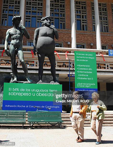 Couple walks past a bronze replica of Michelangelo?s David and its obese version, put by a laboratory on December 1st in support of a campaign...