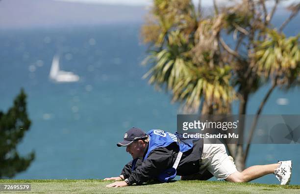 Dominic Bott, caddy for Graeme Storm of England lines up a putt on the 16th hole during round three of the New Zealand Open at Gulf Harbour Country...