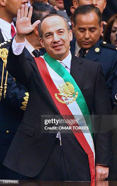 Mexican new President Felipe Calderon waves to his fellows at the Congress in Mexico City, next to outgoing President Vicente Fox 01 December, 2006....