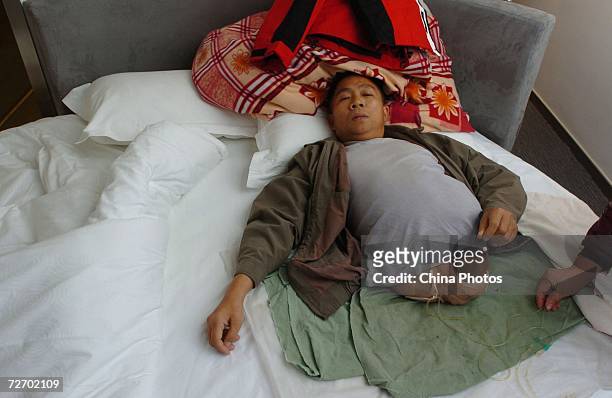 Peng Shuilin lies in the bed at a hotel December 2, 2006 in Beijing, China. Peng Shuilin was hit by a freight truck in a traffic accident in 2004 and...