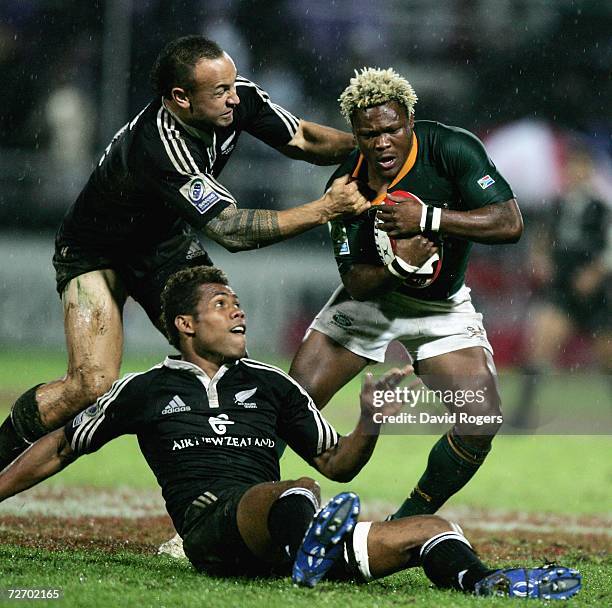 Kabamba Floors of South Africa is held by D J Forbes and Lote Raikabula of New Zealand in the final during the Emirates IRB Dubai Sevens held at the...