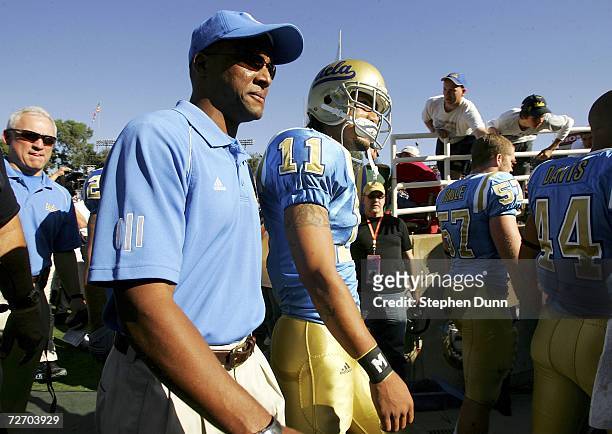 Head coach Karl Dorrell walks onto field with Dennis Keyes of the UCLA Bruins prior to the start of the game against the USC Trojans on December 2,...