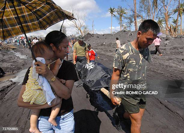 Woman looks at soldiers carrying a body bag over mudflow that buried villages in Padang in Legaspi city 03 December 2006. Rescuers continue to...