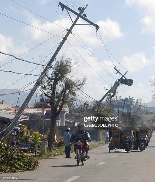 Villagers pass near a fallen electricity post in the eastern Philippine island of Catanduanes 03 December 2006, caused by super typhoon Durian which...