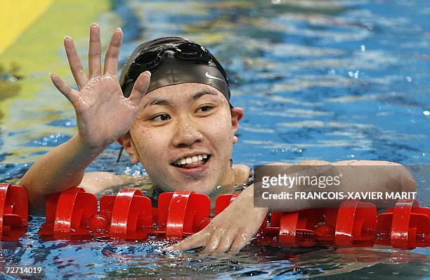 China's Yang Jieqiao waves as she celebrates her victory in the women's 400m freestyle swimming final at the Hamad Aquatic Centre during the 15th...