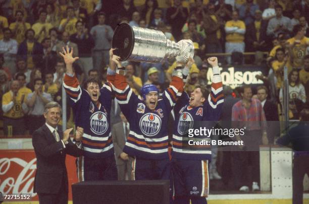 Canadian profesisonal ice hockey player Mark Messier of the Edmonton Oilers hoists the Stanley Cup over his head and shouts as he and teammates Kevin...