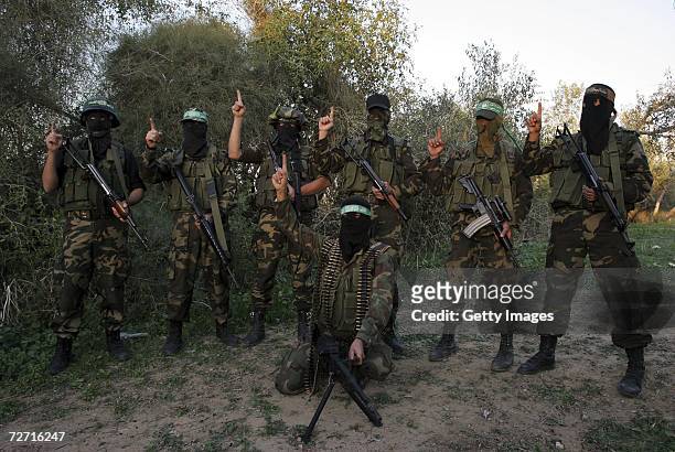 Masked Palestinian members of the Al-Qassam brigade, the military wing of The Islamic Resistance Movement, Hamas, pose during a military exercise on...