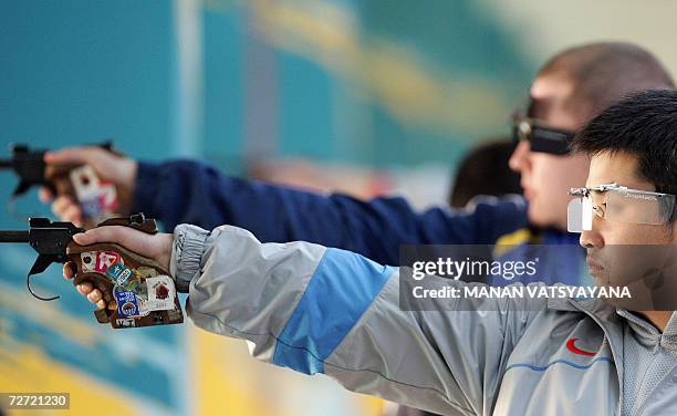 Gold winner Xu Kun of China and silver winner Kazakistan's Rashid Yunusmetov compete in the men's 50m pistol individual final at the 15th Asian Games...