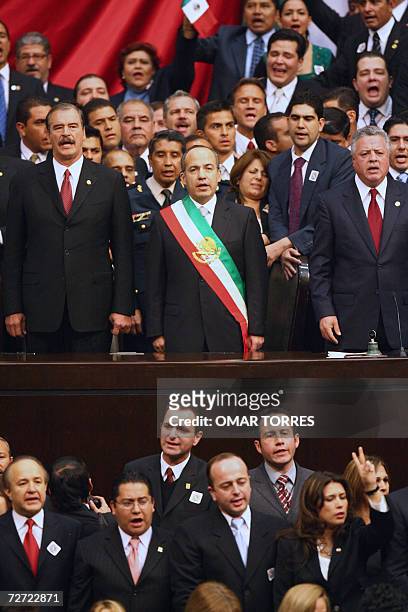 Mexican new President Felipe Calderon outgoing President Vicente Fox and the president of the Chamber of Deputies Jorge Zermeno sing the national...