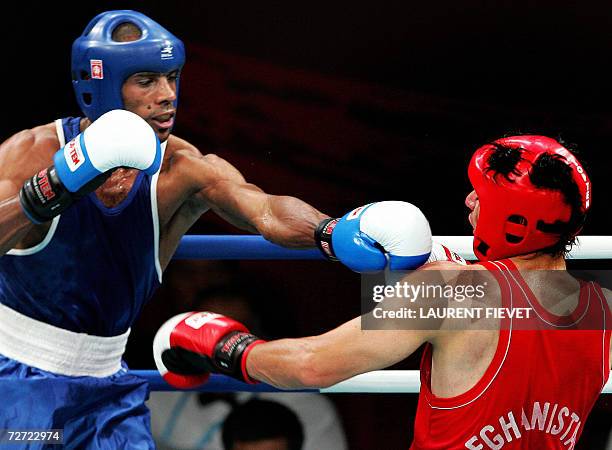 Iraqi Jabar Zuhir throws a punch to Afghan boxer Mohammad Naim Amini in their super lightwight 64kg preliminary bout during the 15th Asian Games in...