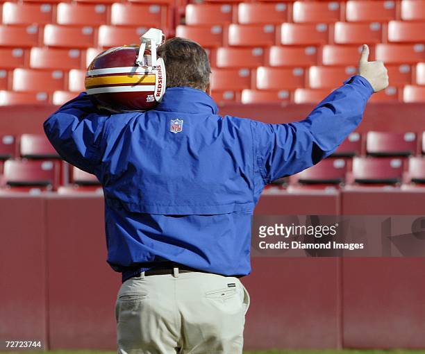 Member of the Washington Redskins staff gives a "thumbs up" signal as he checks the reception in the helmet of quarterback Jason Campbell on the...