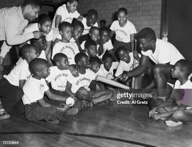 Brooklyn Dodgers Jackie Robinson and Roy Campanella demonstrating some baseball techniques to children at the YMCA in Harlem, 17th November 1948.