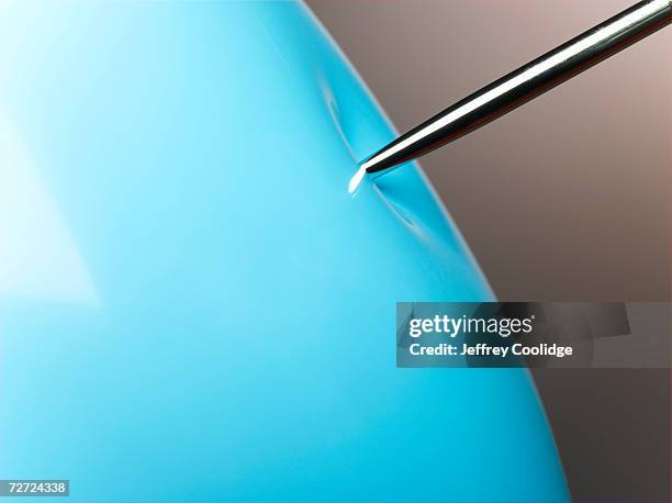 pin pressing on blue balloon, close-up - blowing up balloon stock pictures, royalty-free photos & images