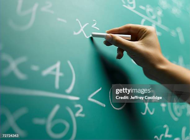 young woman writing on blackboard, close-up of hand (focus on hand) - mathematische formel stock-fotos und bilder