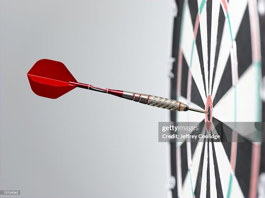 Dart in bullseye of dart board, side view, close-up